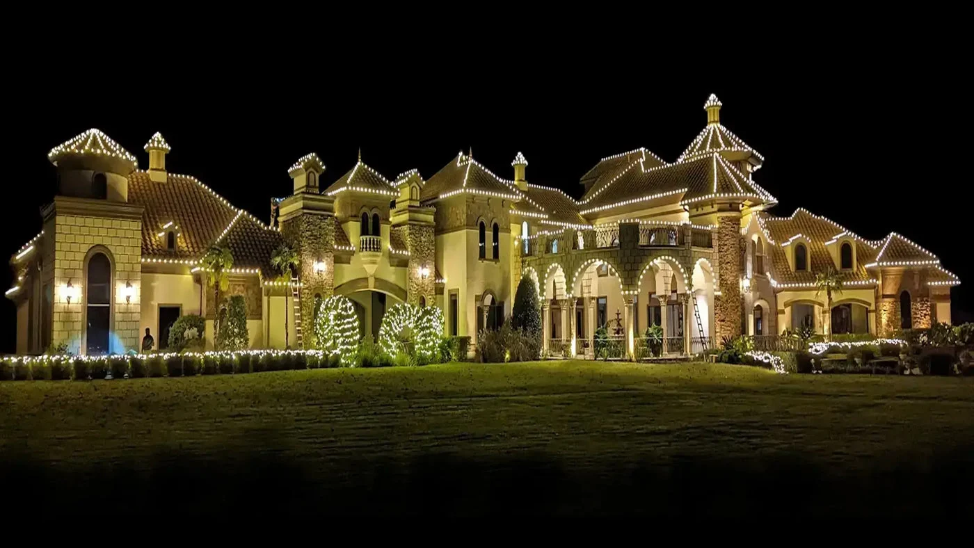 Luxury home with warm white C9 roofline Christmas lights at night
