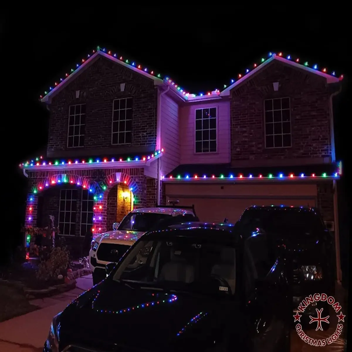 Multicolor Christmas lights on a home with decorated greenery